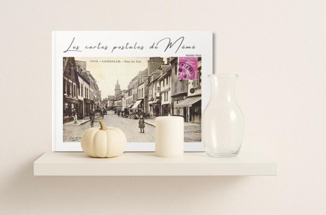 Livre Les cartes postales de Mémé posé sur une étagère avec une bougie et un vase.