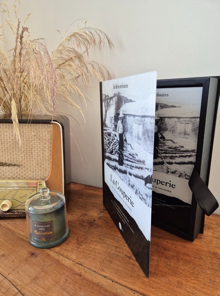 Livre La Couperie posé sur une table en bois, accompagné d'une radio vintage et d'une bougie.